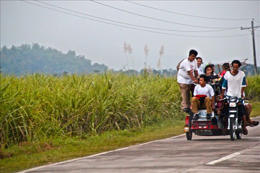 Students go home riding motorcycles in this position due to limited space, some of the houses are located far from the town, some of the houses are located along sugar cane fields