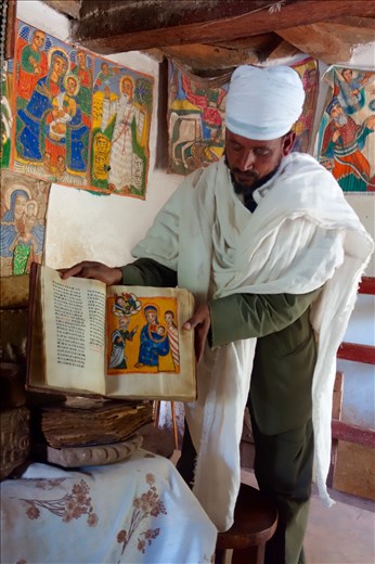 priest displaying 300 yr old Stories of Mary book