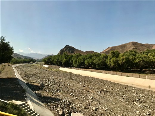 Dry river bed and barren hills on the road to Tian Sham
