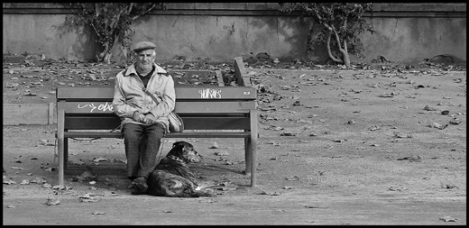 An old man and his muzzled dog sit on the streets of Istanbul, Turkey