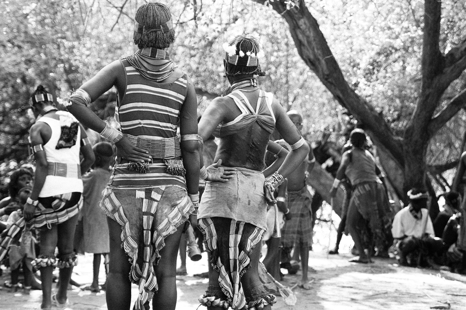 Showing the scars of their whipping are relatives of the boy.  The scars are to show their devotion to the boy about to be a man.   They know that as a man he will be there to help whenever they are in trouble as they have taken pain for him. 