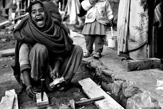 A young girl breaks firewood in a small slum in the Kathmandu Region, Nepal.