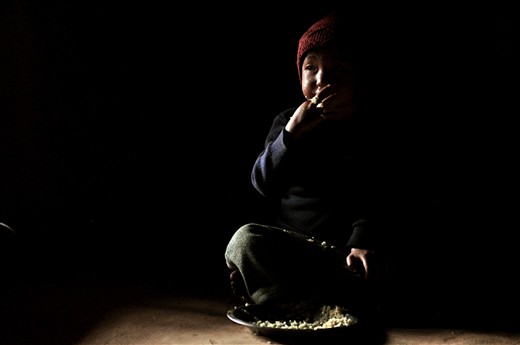 A young boy eats his third meal of rice in his village of Dhading, central Nepal