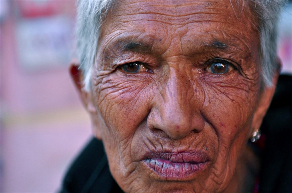 An elderly woman who has been financially supported by EPSA (Entire Power for Social Action) in Nepal poses for a photo in the streets of Kathmandu. This poor woman lives alone with no protection or security and continues to work and labour in order to survive.
