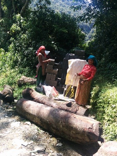 Nepalese women working with concrete blocks stop to smile for a picture.