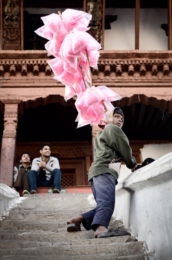 Day or night, the streets of Durbar Square become extremely alive. A young boy selling cotton candy during the festivities finds a viewing point to better spot potential customers.
