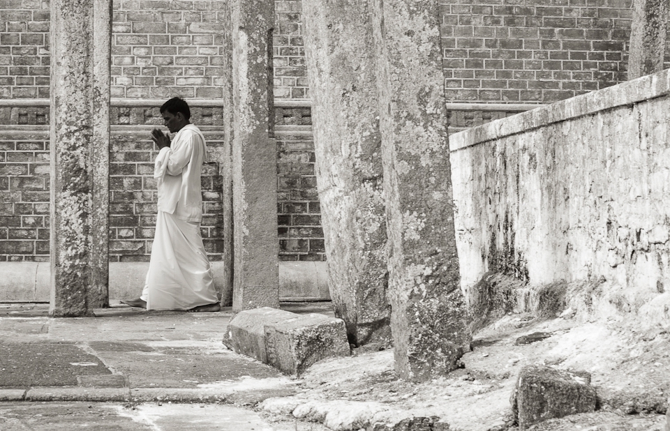 Over a million devotees visit the sacred stupa related places in Anuradhapura, Sri Lanka. Especially during “Full moon Poya” days such as “Poson ”. Stupa’s are strong and inspiring pieces of architecture, drawing to them different people from different walks of life. They all have one thing in common, that is “Hope”.  It is true even with this devotee, who is Circumambulating the “Ruwana Weli Maha Stupa”. 
As he emerges through all the rough textures, you feel that - by and large “Hope” comes into play when our circumstances are “dire”.
