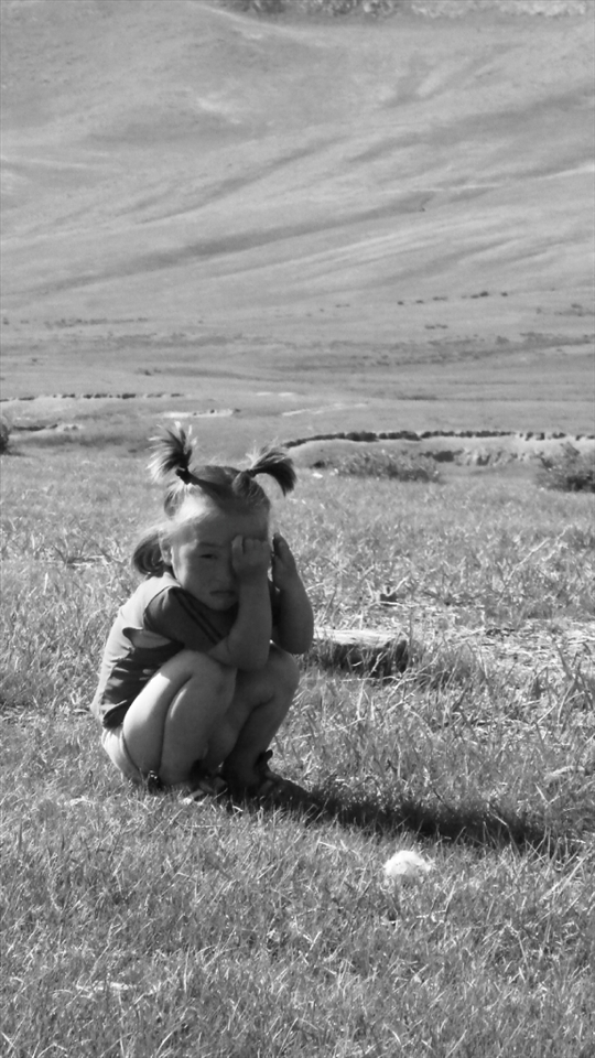 A little girl in a Mongolian nomad family, just woke up from a usual nap on the grass.