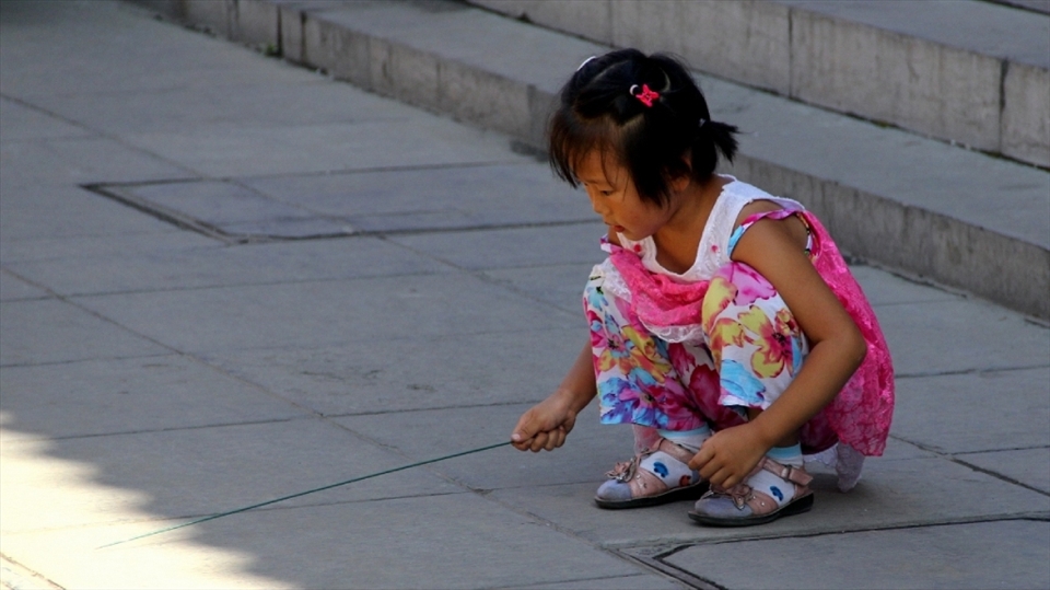 I took this photo just outside a market area in Tianjin, China. With the many pressures that Chinese youth face these days such as increasing competition for a prosperous future and being the only hope in their family due to the one child policy, it is not far-fetched to imagine that this quiet moment of simple play many be one of the rarer moments in this little girls life.