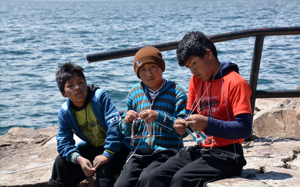 Knitting boys on Taquile - mixture of traditional and modern. There are 3 rules on Taquile - don't steal, don't lie and don't be lazy. So women wave, but man knit (because it's easier than waving). Many tourists visiting the island are told about the traditional customs and offered to buy the knitwear although not all locals wear the traditional clothing. It's a stick with two ends - differences make travelling more interesting, but everyone on Earth must also have equal oportunities and comfort.