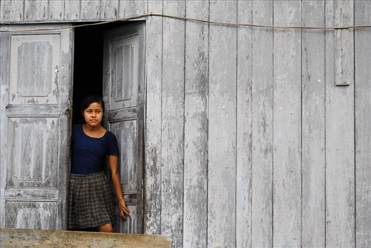 A girl gazes out of her front door, keeping an eye on younger brothers and sisters, in the tiny Amazon village of Nuevo Rocafuerte at the border between Peru and Ecuador.