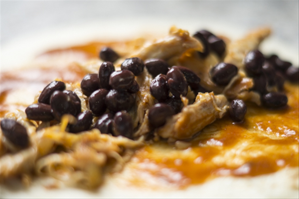 Prior to rolling, chicken, beans and sauce get to knw each other