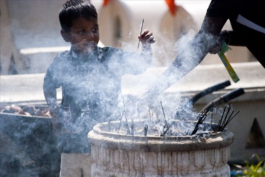 A young devotee burns incense at the Temple. The burning of incense is said to be a symbol of good morality and the cultivation of good moral conduct.