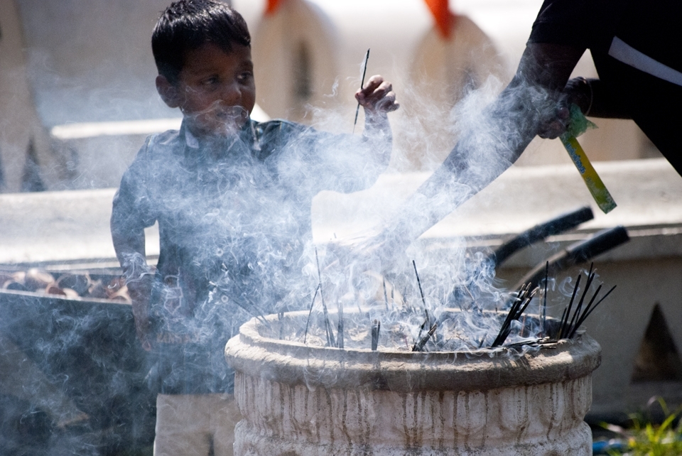 A young devotee burns incense at the Temple. The burning of incense is said to be a symbol of good morality and the cultivation of good moral conduct.