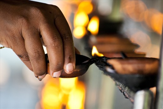 A devotee lights a lamp at the Temple. Light is said to be a symbol of wisdom. The lighting of lamps is said to generate wisdom and dispel the darkness of ignorance.