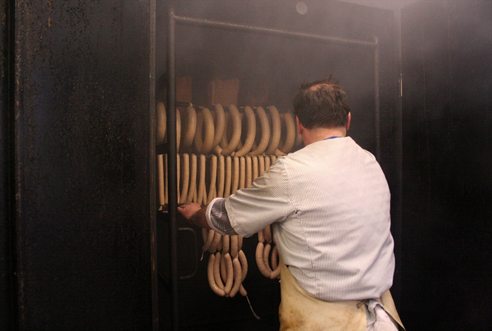 Just like the cows are aligned in the previous image - the sausages are aligned in this shot. Schüll III. puts them in the 
„Räucherkammer“ (smokehouse) to achieve the smokey taste he wants. Doing it the same way as his father and his grandfather, soon, his son will follow. The butchery will carry on for a fourth generation. Every generation has a different story to tell, closely connected to German history. The only constant between the generations is the meat and the given name „Schüll“. 
