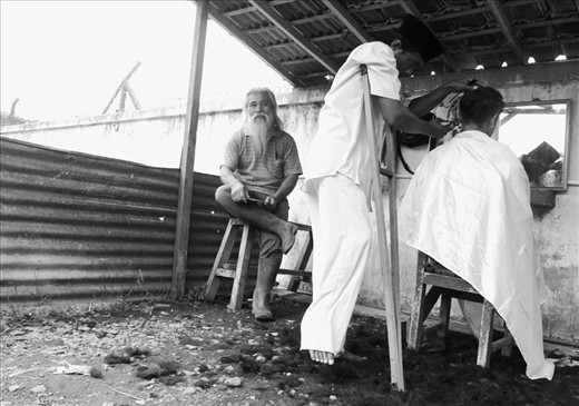 A little barber tent is opened at the corner of the market. It's quite a busy day for the barber because market day is at every five days, so when it's a Sunday, lots of people will come over to have a nice clean hair cut. People will know that this is a good barber based on the amount of hair left over on the ground.