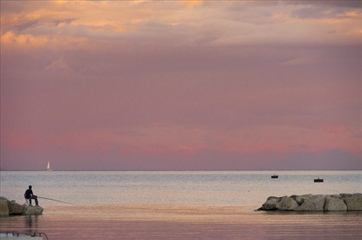 Fishing at Sunset, Gaeta. After a long day working, this boy is relaxing fishing just in front of the pier. Sitting and enjoying the evening breeze.