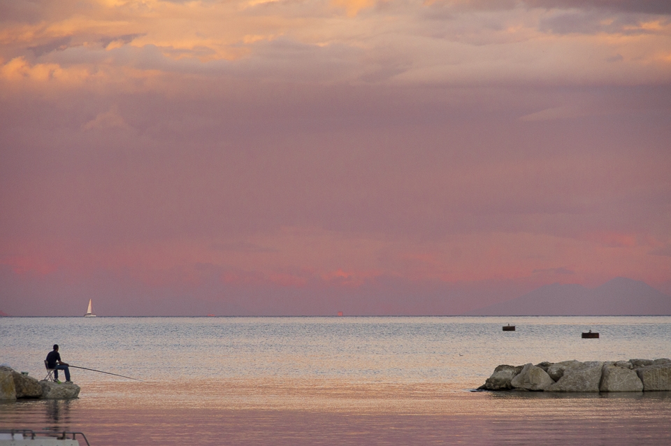 Fishing at Sunset, Gaeta. After a long day working, this boy is relaxing fishing just in front of the pier. Sitting and enjoying the evening breeze.