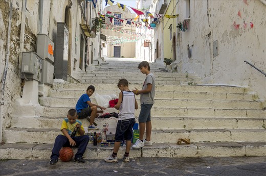Little Entrepreneurs. Gaeta. A group of boys is selling books, comics and toys to foreigners to find money for video games. Town centers are often closed to traffic in small towns, so kids come together and play in the street.