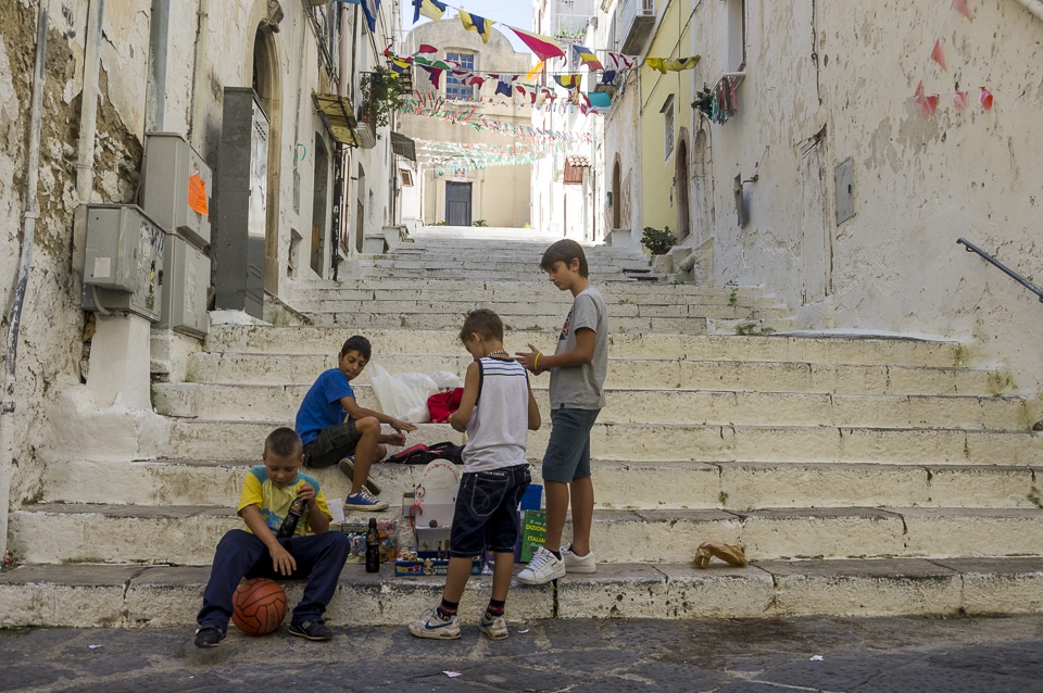 Little Entrepreneurs. Gaeta. A group of boys is selling books, comics and toys to foreigners to find money for video games. Town centers are often closed to traffic in small towns, so kids come together and play in the street.
