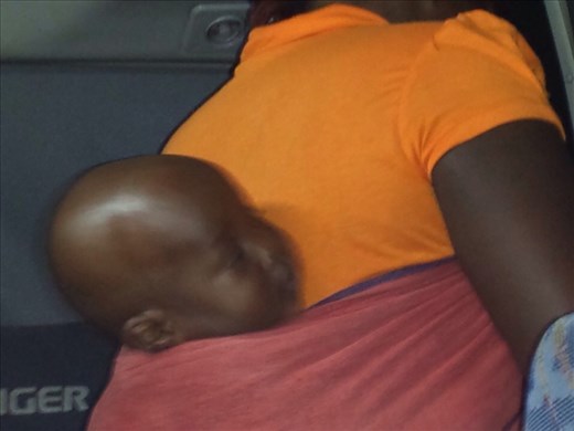 Baby tied to mothers back as they enter a bus.
