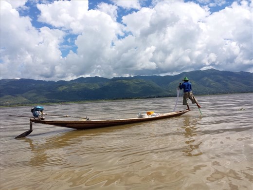Great coordination. Net fisherman using both hands to pull in a net while paddling the boat with his foot and leg.