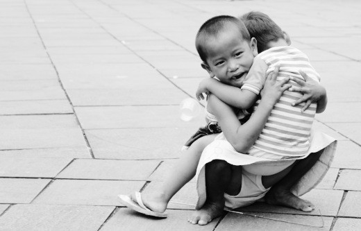 A child holding the younger one and he looks like he's crying.