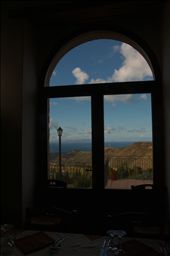 La Cucina: The second thing of I think of, when I remember Sicily. Food glorious food, wonderful food. Oh the food, so simple, yet so delicious and so fresh. This photo was taken at Mortizzi, another small village, up another extremely windy goat track, on the side of a hill. This is the village where my Dad was born and before my dad left Italy, the village consisted of two houses (a white house and a pink house). Since then, the owners of the land (still the same family that owned the land when Dad lived there) have built a restaurant (Villa Rica) and converted the pink and white houses into a Bed & Breakfast. The restaurant was closed when we visited, but the owner (the son of the original owner) invited us in for some food, and a vino and a chat. The guy was probably at least 80 years old and remembers my Nonno and Dad. He told stories of how my family used to cultivate the land for his father- oranges, olives, stone fruit, wheat - and in return my family would get to live in the white house for free and keep half of the produce to sell. Nonno used to also manually press the olives with the olive press to make oil. The press is now a feature in the restuarant. This photo is taken from inside the restaurant overlooking the fertile volcanic soil, that is used to grow most of the produce that is used in Villa Rica, and other restaurants around town. In the foreground you can see a table set, ready for evening visitors to the restaurant. I love how the window frames the 'bella vista' of the fertile land and the Aeolian Islands in the distant background. : by lisag_13, Views[604]