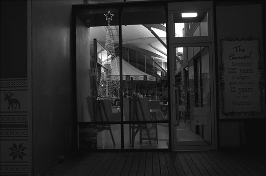 Christmas tree reflected in the window that houses the old carousel 