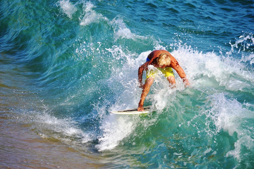 A little bit further, a man aims to find his own equilibria amongst ocean waves