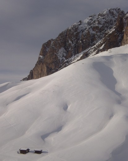 A shack sits on the mountainside, isolated and dwarfed by a relatively small peak on the Dolomites, near Campitello.
