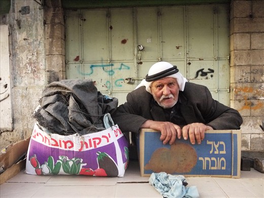 #2 A Weary Merchant:  Taken after a day of hustle and bustle in the markets, this portrait captures the weariness of a senior citizen after a day spent shifting produce in the heat. His posture, his work-worn and sweat-varnished face, the slight glow from the setting sun, his dusty jacket, along with his subtle grin, make this one of my favourite shots. It’s almost as if he’s had to use his last bit of strength to acknowledge the camera, before he slumps for some well earned rest. I was pleased that his friendly nature was able to shine through in the shot. The juxtaposition of the Hebrew text and Arab attire adds an interesting footnote to the shot, somewhat suggestive of the region.