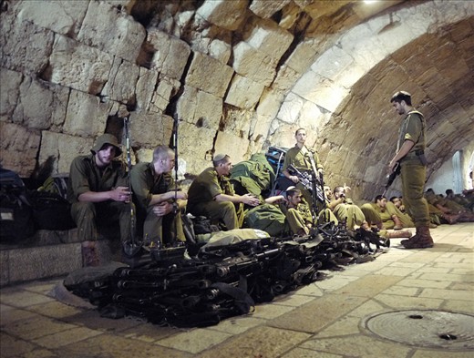 #4 A Moments Rest:  It seemed wherever I was in Jerusalem, I was never far from soldiers. I’d seen a machine gun before, but never a large, neatly stacked pile of them.  I was a little apprehensive about pulling my camera out, but thought I’d regret it if I didn’t. I was given a friendly nod from one of the soldiers, meaning approval was granted, and subsequently took the photo. I think this shot, taken in the old city, accurately reflects the mood and disposition of many of the young, off-duty soldiers I saw. They generally appeared relaxed and chatting, which always made for an interesting juxtaposition when cast against machine guns. There was also a strong sense of comradery between the groups of soldiers I saw, which seems to be typical of young Israelis today. It can be seen not only in the foreground, with the soldier smiling whilst chatting to those seated, but also further back in the shot, where soldiers are all laying down next to each other across their backpacks, limbs intertwined.