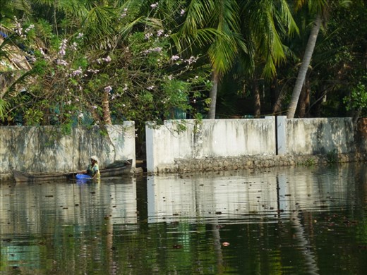 Hot and still on the water a woman wades into the water to collect bottles, litter from the city, to sell. 