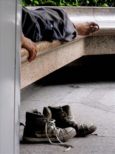 A homeless man rests his feet outside a subway station on Hong Kong Island.