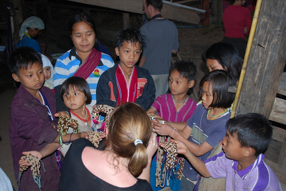 A new group of tourists  are greeted by the village children hoping to sell their jewellery. 
