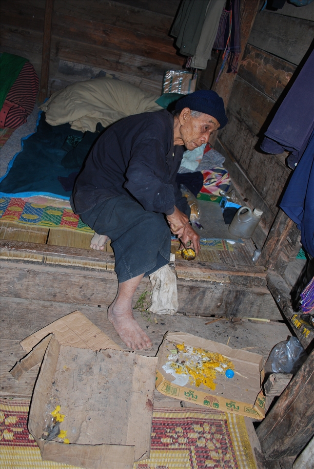 An elderly man helps prepare food for a group of tourist.