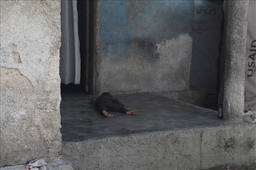 While out on the ground one day, I noticed this child laid lifeless on a cold concrete porch. His Father sat drinking a few metres away, going insane because of our presence. Unable to approach the child I hoped he was okay. I snapped this shot with my camera down by my side, in order not to provoke the childs drunk Father.  