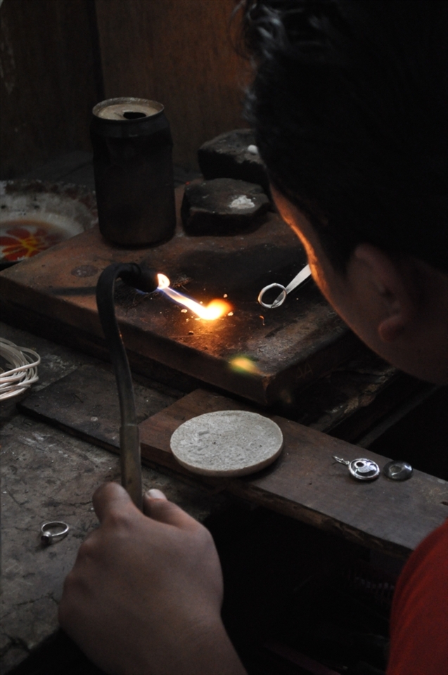 Hard at work.  A Balinese jewellery maker turning a silver ring. This factory is one of Bali's largest manufacturing and exporter of jewellery.  Work safety conditions would be illegal here in Australia but not the case in Bali