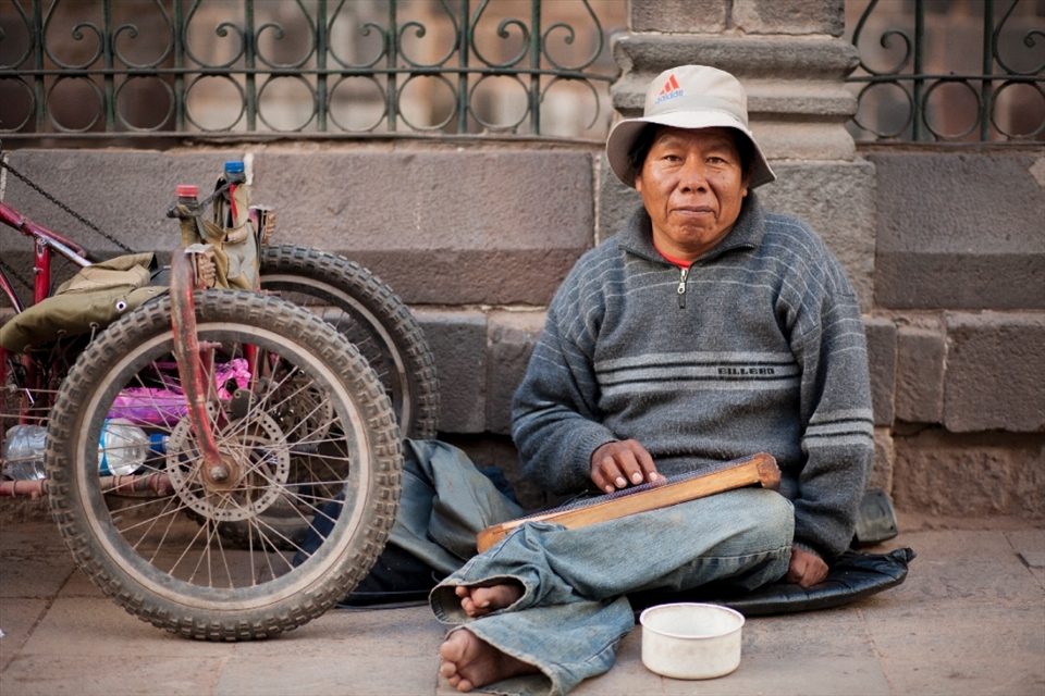 With no use of his legs, this man has a modified hand-pedaled trike he uses to transport himself around.  He plays music on a hand-made walaycho, a Peruvian stringed instrument, to make a living.  San Pedro Marketplace, Cusco, Peru.