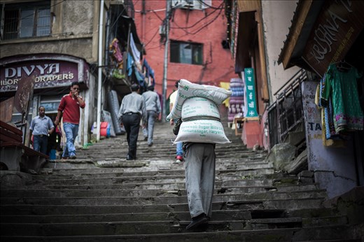 Amin, 46, left his home in neighboring Nepal where the chances to find a job came to naught and tried his luck in India. Following the same route every day, he carries heavy bags full of sugar from the warehouse to the shops. Almost all of his salary Amin sends to his family – they are waiting for his return at home.