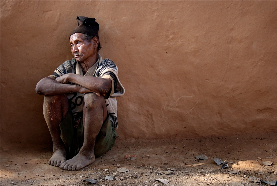 A subsistence farmer, he lives from hand to mouth.  Separated from the group, this weathered Chepang man leans against a mud house in sombre reflection. 