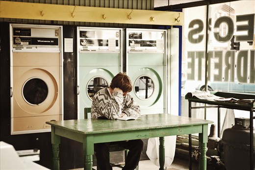 WATCHING, WAITING 
The Laundromat is a quiet place where people wait patiently for their washing- oft reading or catching up on study or generally just enjoying the solitude, observing the cyclic movement of their clothes drying. Most appear completely unaware of the rattle and tumble of the old washers. The constant hum of the machines and the swishing of water and fabric is soothing, an unexpected serenity within an industrial work place.
