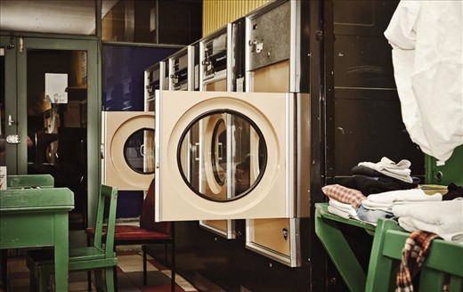 THE END OF A LONG DAY The Laundromat is a mess at the end of a long day. Machines are left open; chairs are out; a pile of washing sits neatly folded, waiting to be taken home. The constant thoroughfare leaves the Laundromat tired.