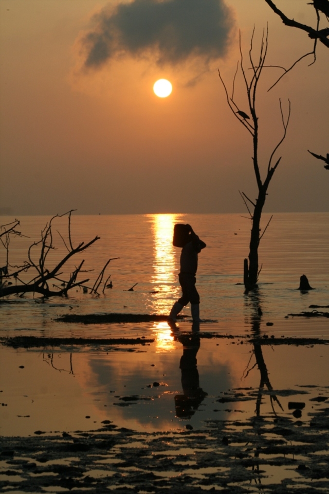 FISHERMAN WALKS ON SHORE OF LAKE