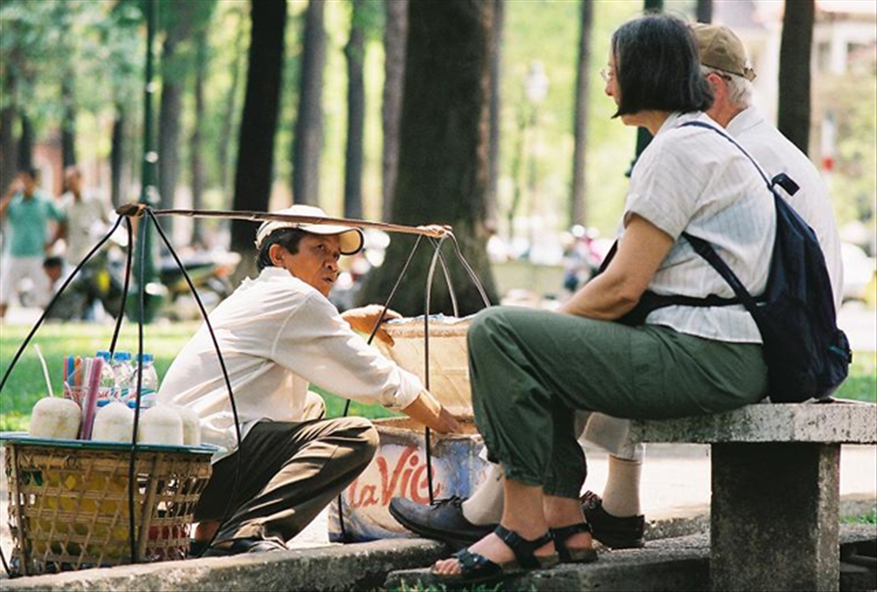 A vendor is serving cold coconut juice for a foreign couple. 