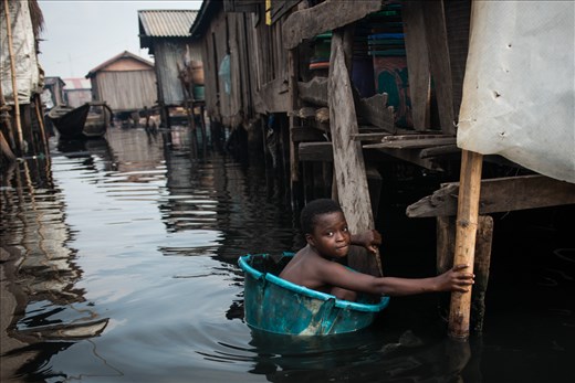 A young boy swims in through dirty oily water of Nigeria's Makoko slum. 30 April