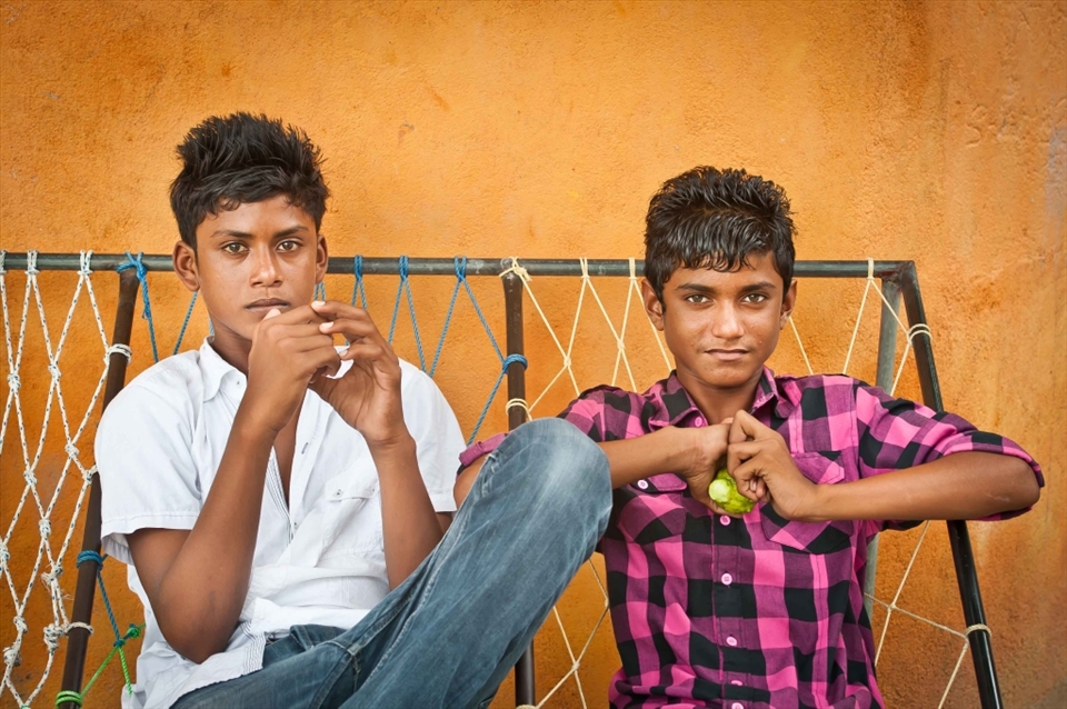 Two Maldivian teenagers relax in the street. Most island settlements feature small Islamic schools where children are taught in small classes.