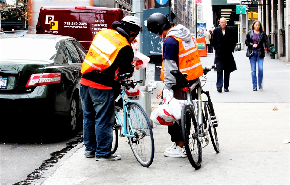 A couple of Latin immigrants working as delivery boys try to figure out the location of their next job in the Lowe East Side of Manhattan. Although hardly perceived by the passers, they constitute the larger majority during lunch hour as they transport the meals. 